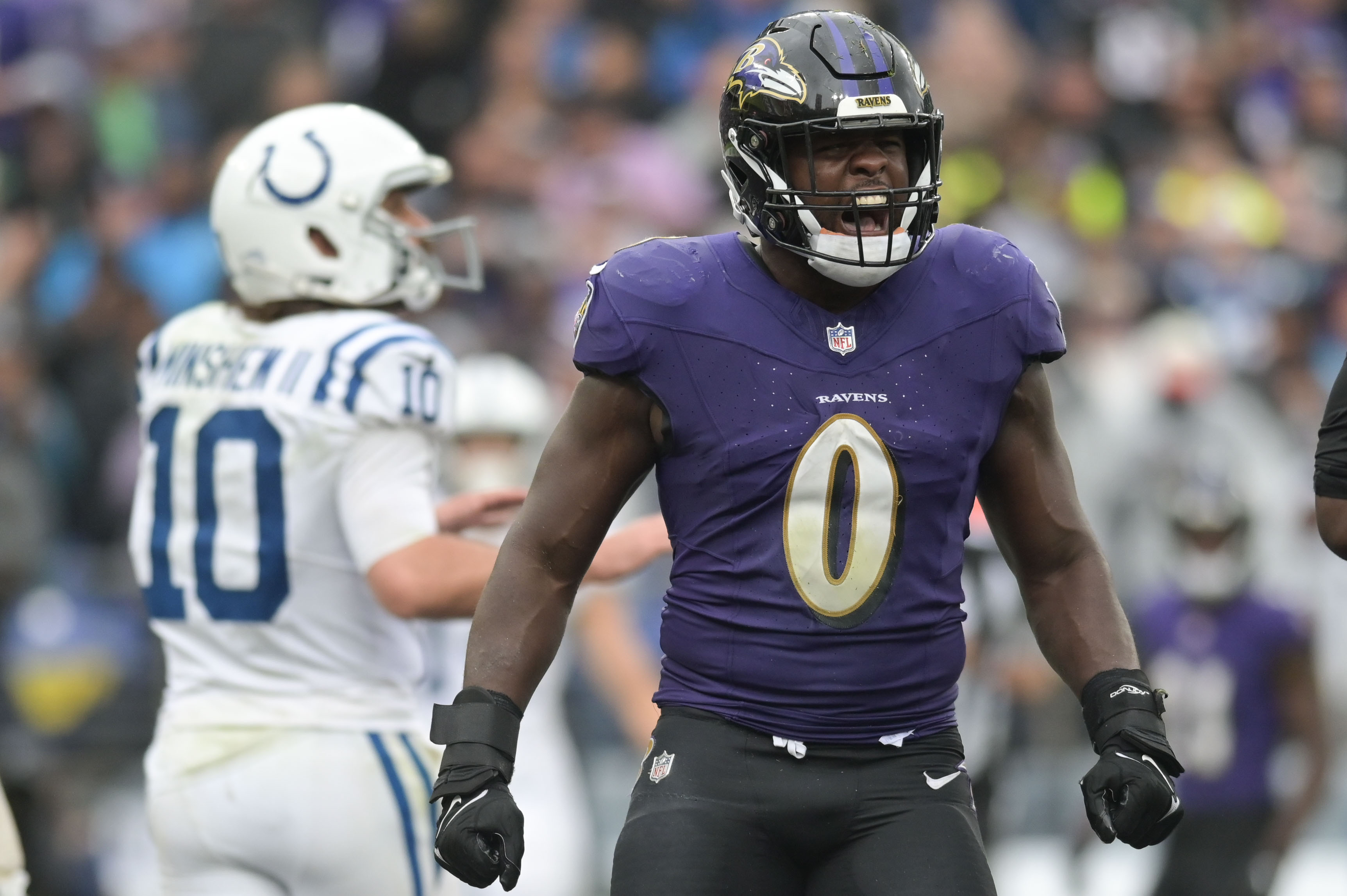Roquan Smith yells in celebration on the field as Colts QB Gardner Minshew walks behind him